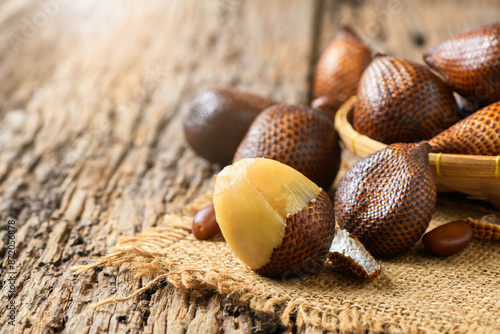 Salak (Salacca zalacca) or Snake fruits on sack and on old wood background, Thai fruits photo