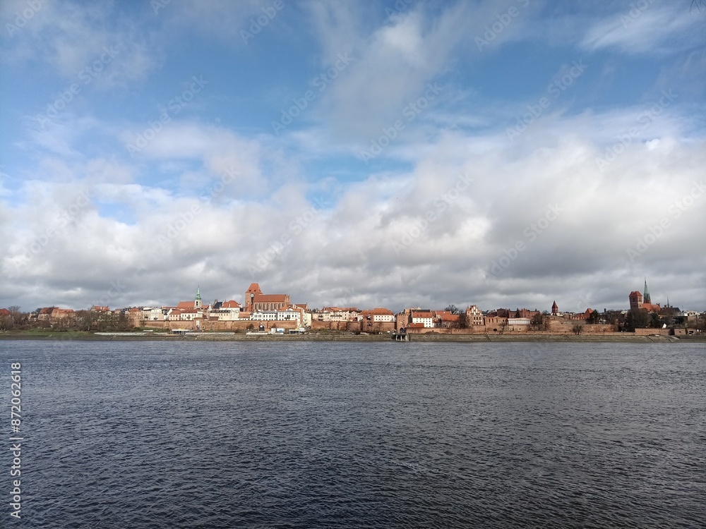 A photorealistic image of a wide river with a pedestrian walkway and buildings on the opposite bank. A photorealistic image of a wide river with a pedestrian walkway and buildings on the opposite bank.