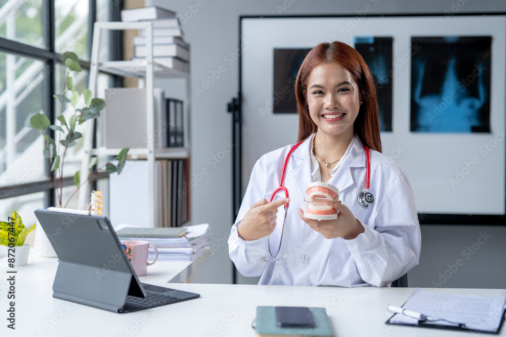 A woman in a white lab coat is holding a dental model and smiling A woman in a white lab coat is holding a dental model and smiling