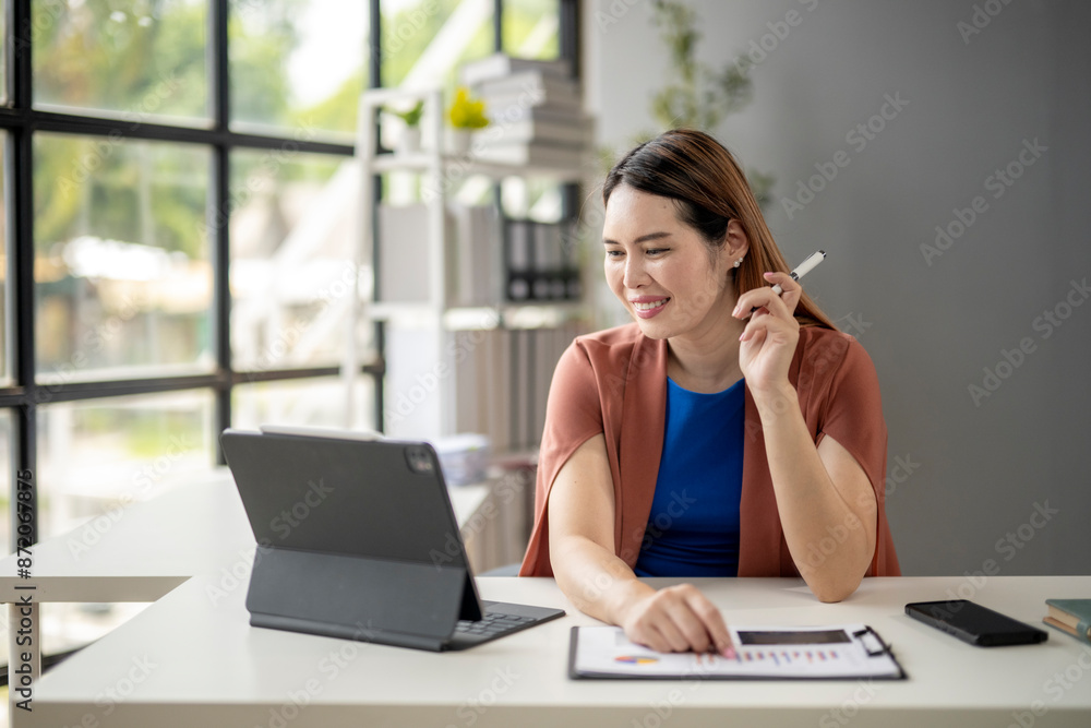A woman is sitting at a desk with a laptop and a tablet A woman is sitting at a desk with a laptop and a tablet