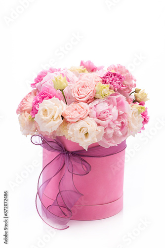 Bouquet of pink peony roses in a pink round box with ribbon on a white background