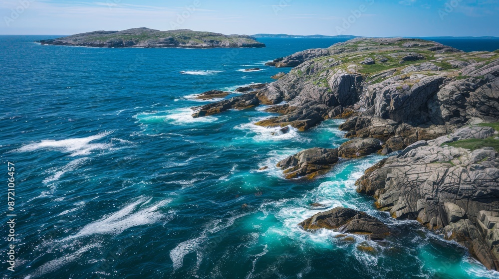 Fototapeta premium Aerial view of rugged northern coastline, waves hitting rocky shore, bright clear day, blue waters