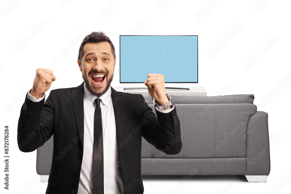 Young businessman gesturing happiness in front of tv and looking at camera Young businessman gesturing happiness in front of tv and looking at camera
