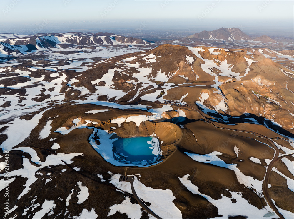 View from above, stunning aerial view of the Krafla Viti crater. This beautiful Crater is filled with blue water and surrounded by a geothermal area and colorful mountains. Iceland.