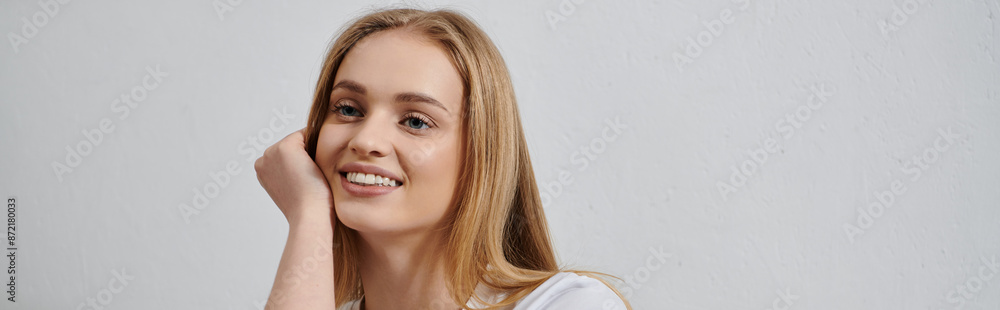 A young woman with blonde hair smiles warmly while relaxing at home. A young woman with blonde hair smiles warmly while relaxing at home.
