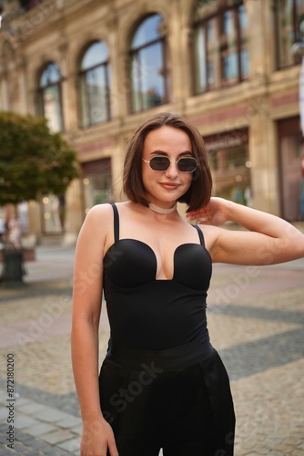 portrait of a woman, of a brunette in sunglasses and a black business suit on a city street