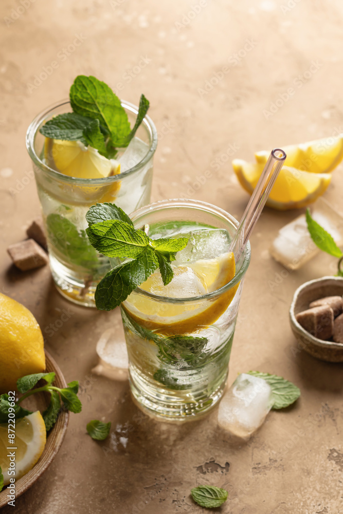 Two glasses of mojito cocktail or tonic with lemon, mint and ice on brown textured background. Refreshing summer drink Two glasses of mojito cocktail or tonic with lemon, mint and ice on brown textured background. Refreshing summer drink