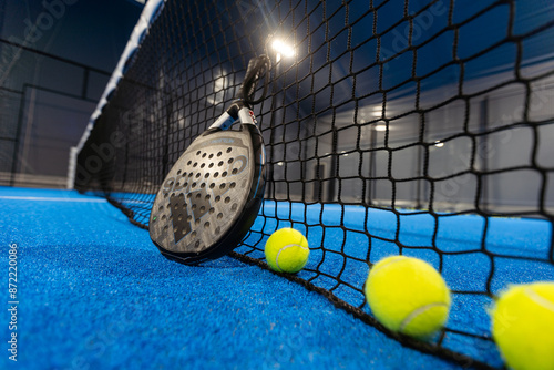 Kyiv, Ukraine, April 18, 2024. Black professional paddle tennis racket and ball with natural lighting on blue background. Horizontal sport theme poster, greeting cards, headers, website and app photo