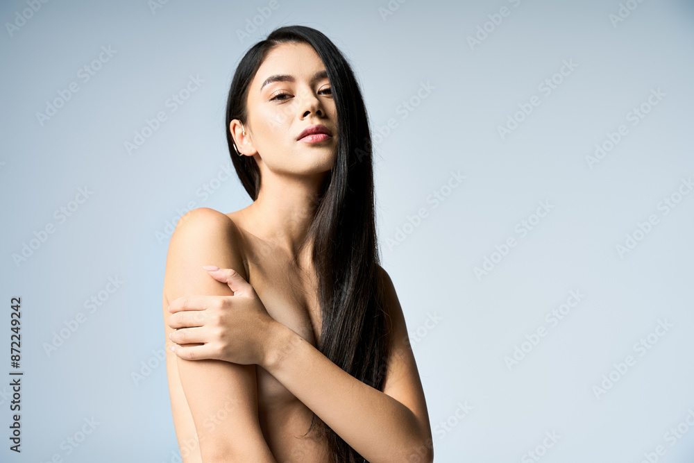 Obraz premium A young woman with long black hair poses confidently in a studio setting.