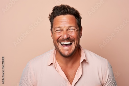 Portrait of a happy mature man laughing against a pink background.