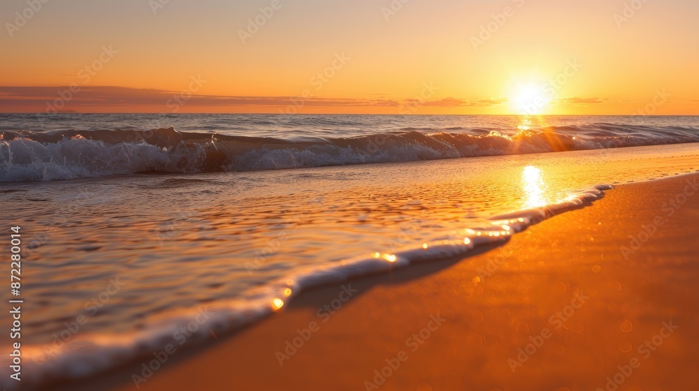 Naklejka premium Serene Beach Sunset Scene with Reflecting Orange Glow