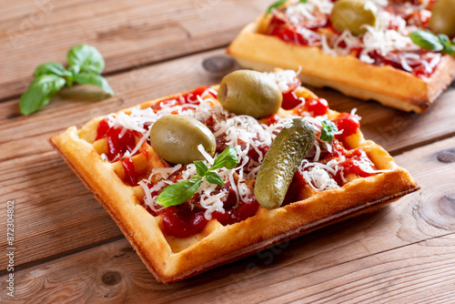 Pizza waffle toast with tomatoes, cucumber, olives, sausages, cheese and herbs on a table photo