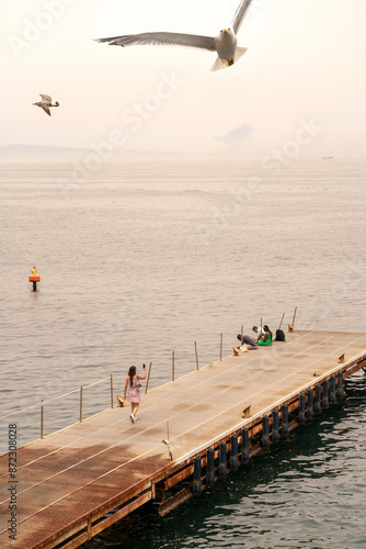 Sorrento, Italy - June 29, 2024: View of the sea and the beaches with tourists taking selfie with camera and sea gull birds flying around