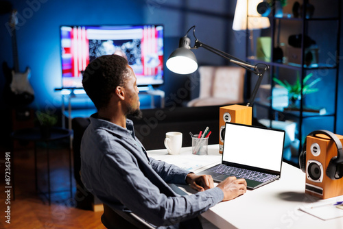 Freelancer looks at white screen on laptop while working remotely, using blank template on display and improving his skills at home. Developer enjoying self training course program.