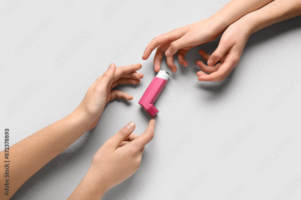 Child's hands with asthma inhaler on white background