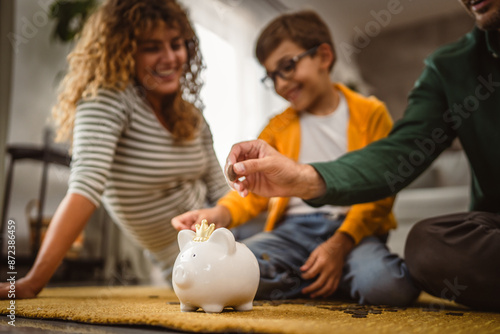 Bild auf Leinwand mam dad and son sit on the carpet and save money in the piggy bank