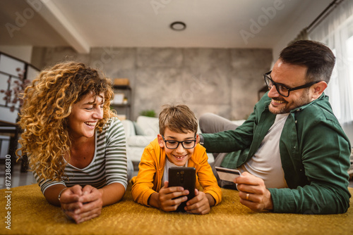 Mum,dad and son have online shopping on mobile phone with credit card © Miljan Živković