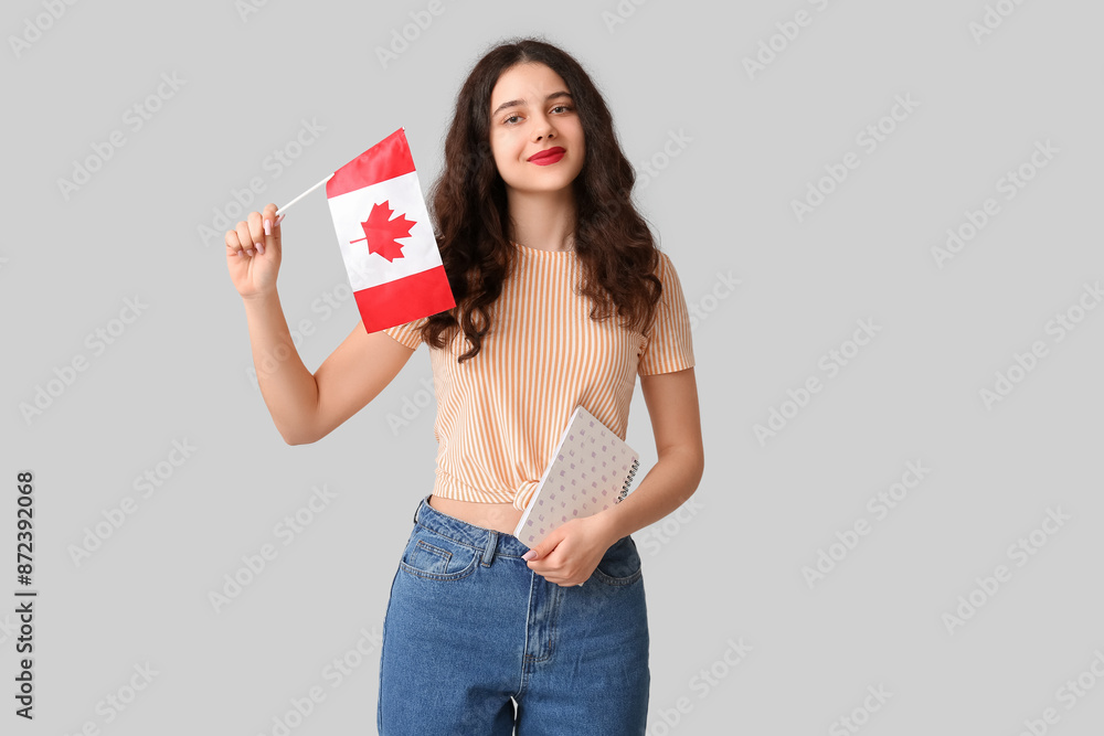 Female student with flag of Canada and notebook on grey background Female student with flag of Canada and notebook on grey background