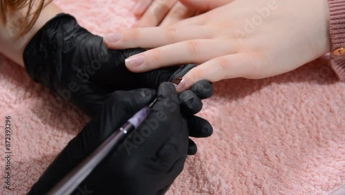 Beautician applying special clear nail polish to a female nails in a beauty studio, concept of manicure and beauty