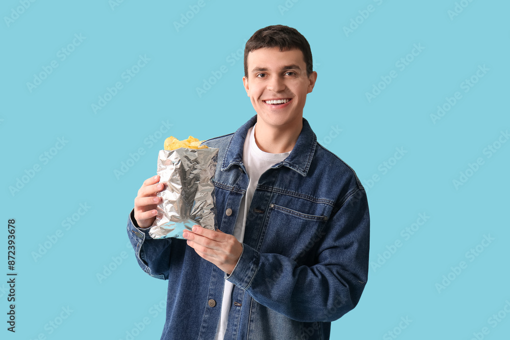 Young man with potato chips on blue background Young man with potato chips on blue background