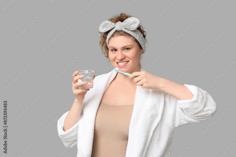Beautiful young happy woman with toothbrush and glass of water on grey background Beautiful young happy woman with toothbrush and glass of water on grey background