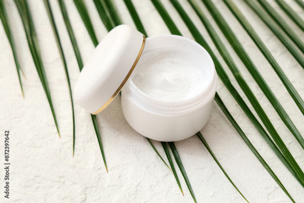 Jar of natural cream and palm leaf on light background Jar of natural cream and palm leaf on light background