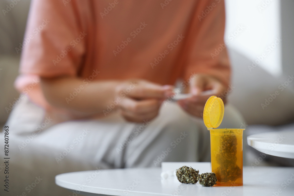 Bottle with weed on table of woman after chemotherapy at home, closeup Bottle with weed on table of woman after chemotherapy at home, closeup