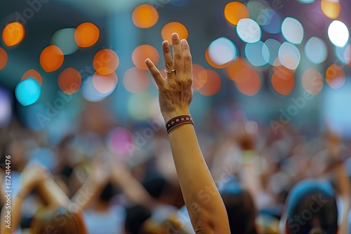 A woman is holding her hand up in the air in a crowd of people. Concept of unity and togetherness, as everyone is gathered in a large group