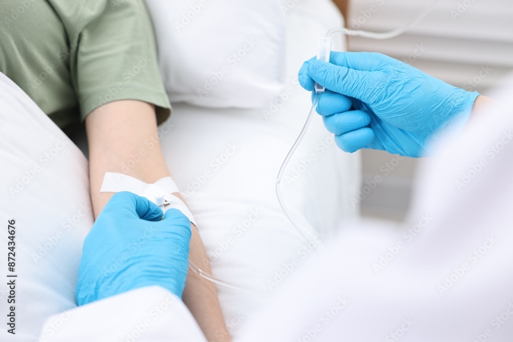 Nurse inserting IV into arm of patient in hospital, closeup Nurse inserting IV into arm of patient in hospital, closeup
