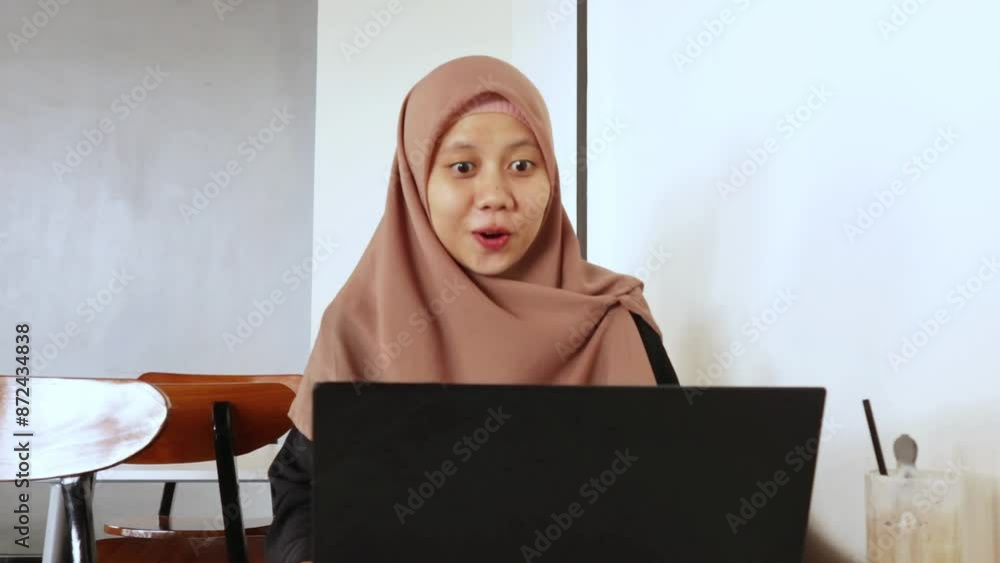 A young Muslim woman is chatting happily using a video call on her laptop A young Muslim woman is chatting happily using a video call on her laptop