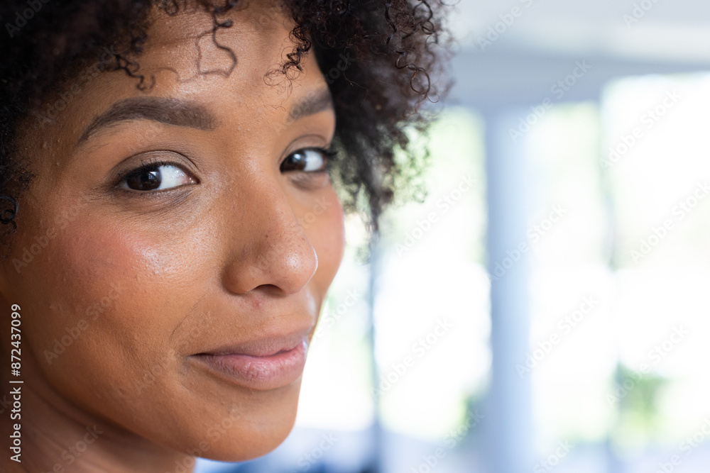 Smiling woman with curly hair looking at camera in bright home setting, copy space Smiling woman with curly hair looking at camera in bright home setting, copy space