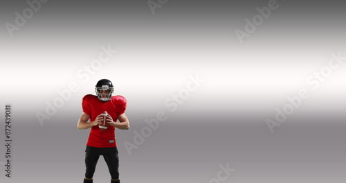 Male rugby player wearing helmet holding rugby ball celebrating against grey background