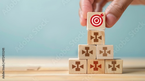 Strategic Success Hand positioning bullseye icon on stack of goalreaching blocks with upward arrows. Light blue background for focus and clarity.