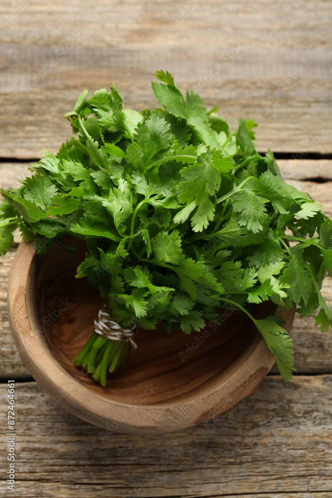 Bunch of fresh coriander in bowl on wooden table, top view Bunch of fresh coriander in bowl on wooden table, top view