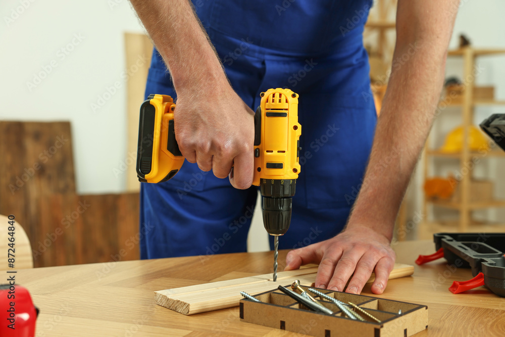 Craftsman working with drill at wooden table in workshop, closeup Craftsman working with drill at wooden table in workshop, closeup