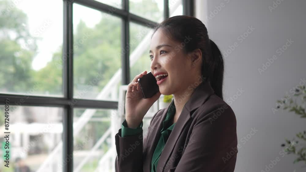 Professional businesswoman in office, talking on phone by window. Slow-motion footage shows her emotions and gestures during the conversation Professional businesswoman in office, talking on phone by window. Slow-motion footage shows her emotions and gestures during the conversation