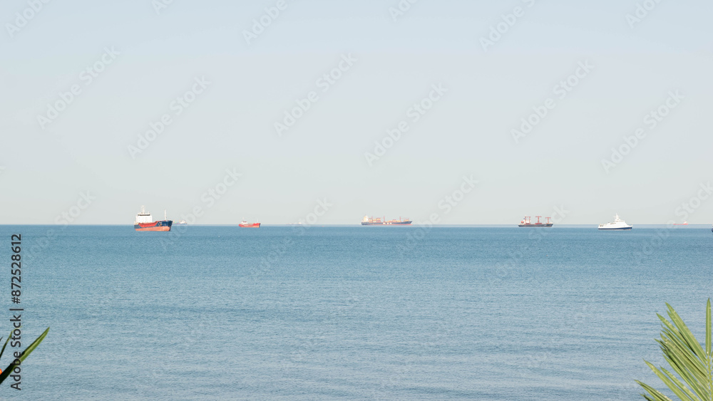 Cargo Ships and Boats on Calm Blue Sea Horizon on a Clear Day Cargo Ships and Boats on Calm Blue Sea Horizon on a Clear Day