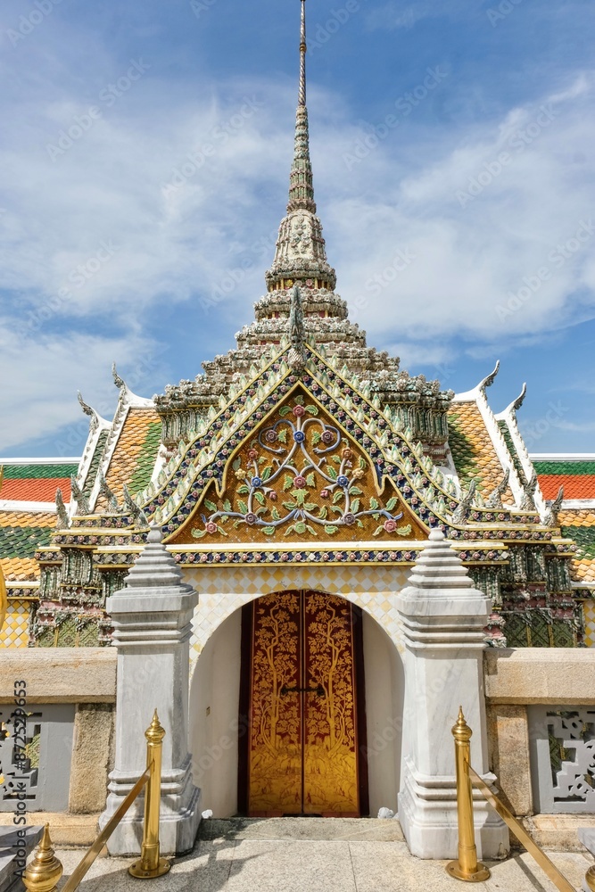A side gate between the the Temple of the Emerald Buddha (Wat Phra Kaew) and the Grand Palace with ornate, decorative glazed ceramic tiles in Phra Nakhon, Bangkok, Thailand on a sunny day A side gate between the the Temple of the Emerald Buddha (Wat Phra Kaew) and the Grand Palace with ornate, decorative glazed ceramic tiles in Phra Nakhon, Bangkok, Thailand on a sunny day