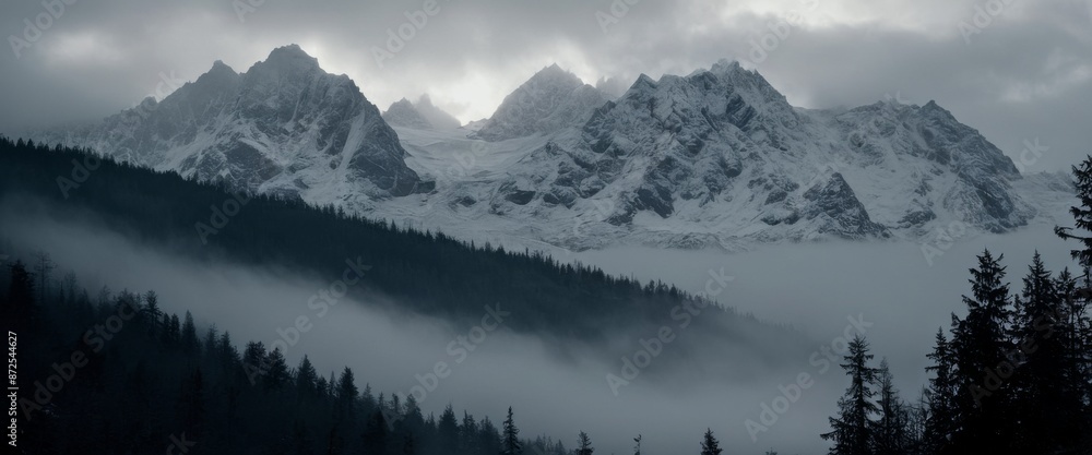Stunning mist covered forest Ominous Jagged snow-capped mountain Stunning mist covered forest Ominous Jagged snow-capped mountain