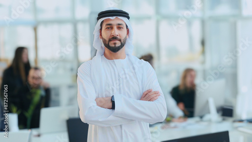 Professional Arab UAE Emirati man using smartphone on call. Happy Middle Eastern national wearing kandura at a business corporate location