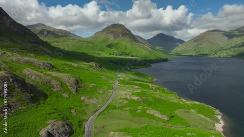 Dark lake surrounded by mountains on overcast day with lakeside road. Lateral drone move over lake. Yewbarrow and Great Gable visible. Wastwater. Wasdale, Lake District, Cumbria, England, UK photo