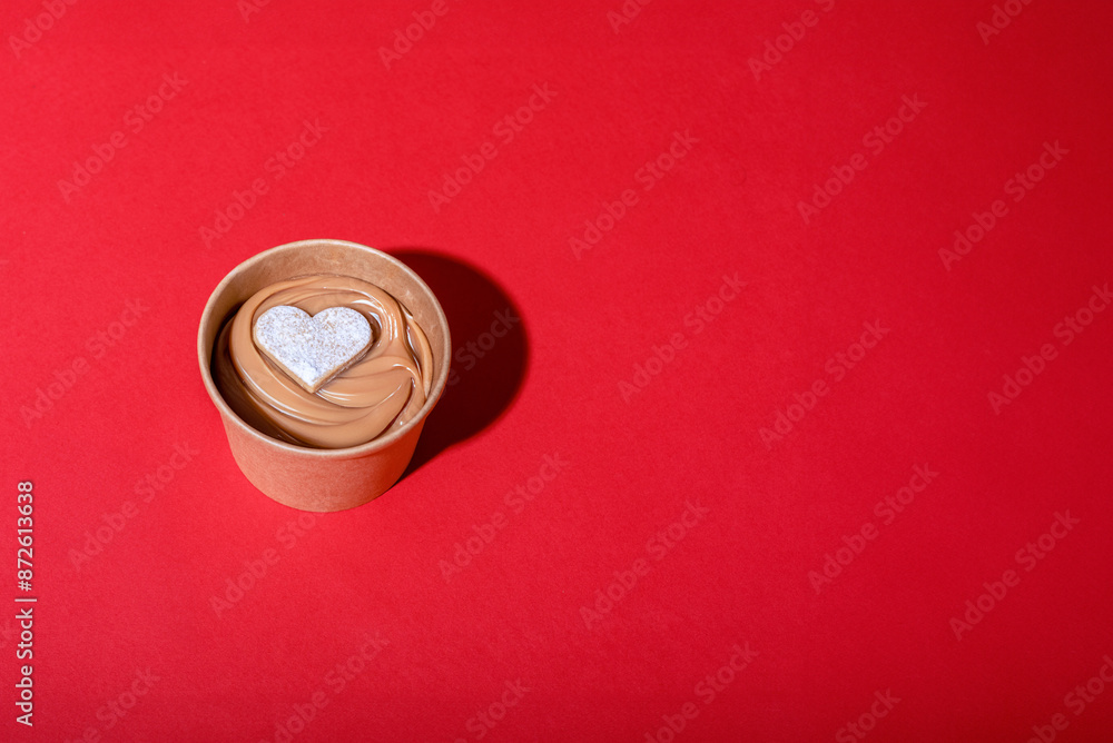 Dulce de leche with an alfajor heart on red background. Copy space. Dulce de leche with an alfajor heart on red background. Copy space.