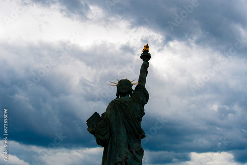 Statue de la liberté vue de derrière à contrejour (silhouette), face à un ciel de nuages d'orage. Concepts de menace et de danger pour la liberté et pour la démocratie