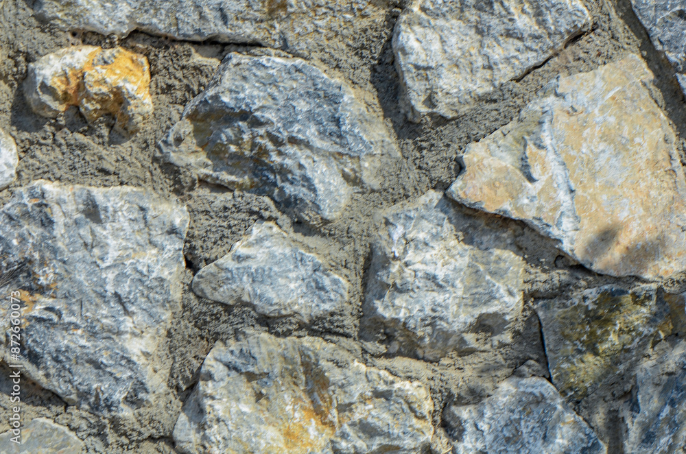 Fototapeta premium fence real stone wall surface with cement on white sky background.