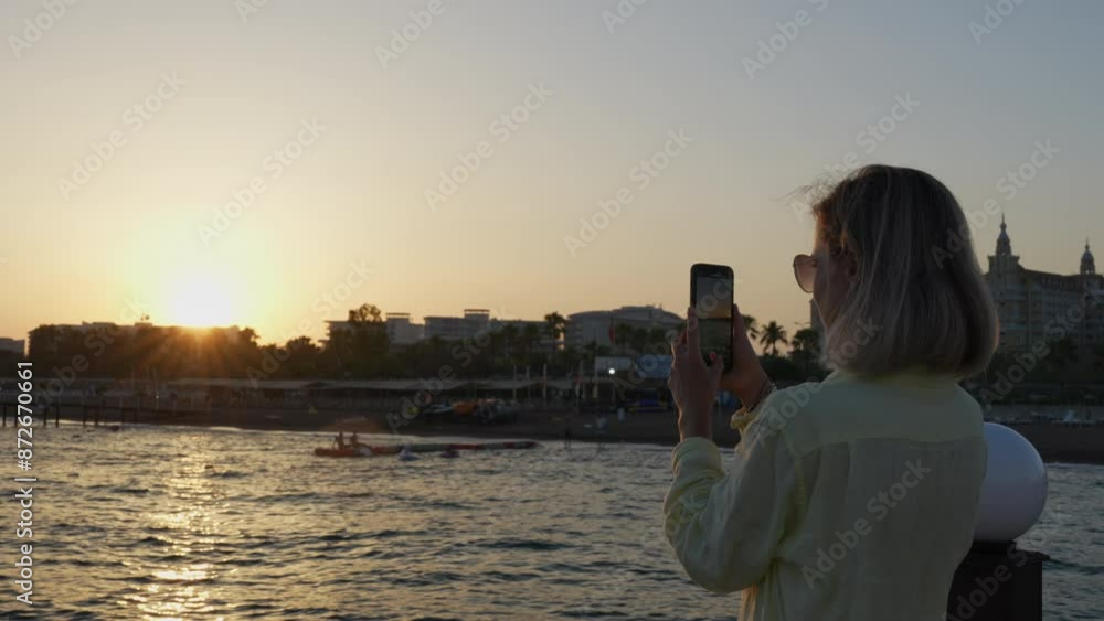woman shooting video of sunset on the beach woman shooting video of sunset on the beach