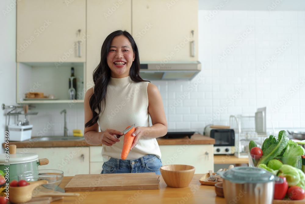 Exercise, diet, maintaining figure, fresh food that is important for losing weight and perfect health. Beautiful Asian woman peeling and chopping carrots to make a salad to eat at home. Exercise, diet, maintaining figure, fresh food that is important for losing weight and perfect health. Beautiful Asian woman peeling and chopping carrots to make a salad to eat at home.