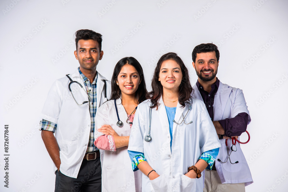 Group portrait of four indian asian young doctors in uniform standing against white background Group portrait of four indian asian young doctors in uniform standing against white background