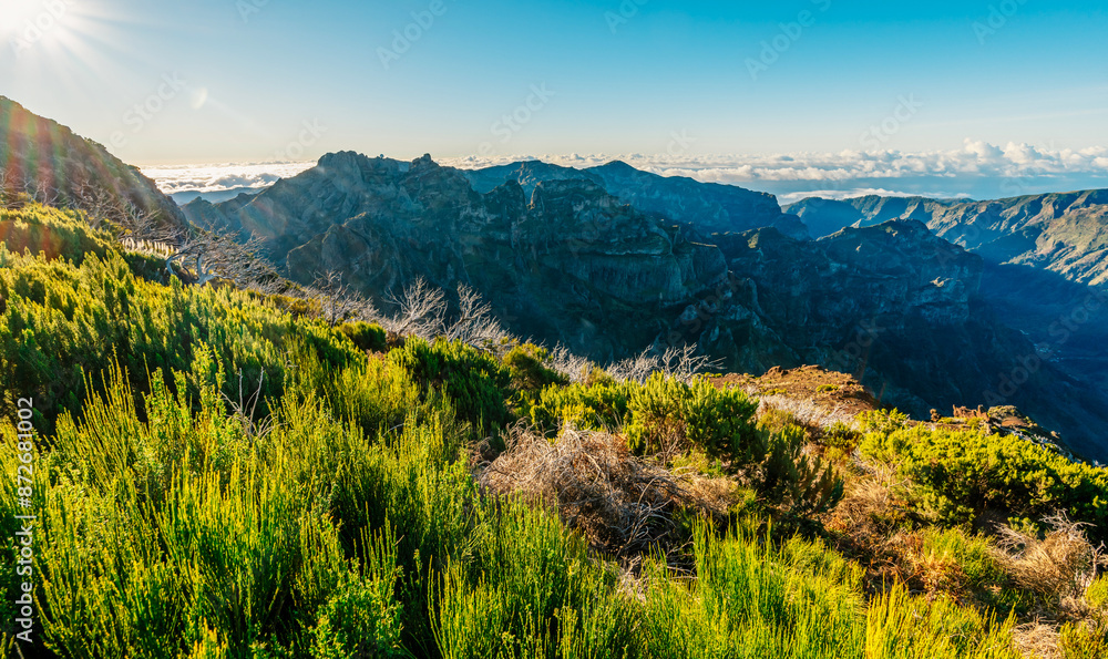 Fototapeta premium Hiking on the highest peak of Madeira Pico Ruivo next to the cottage Abrigo do Pico Ruivo. Views of the surrounding mountains lanscape during sunny day