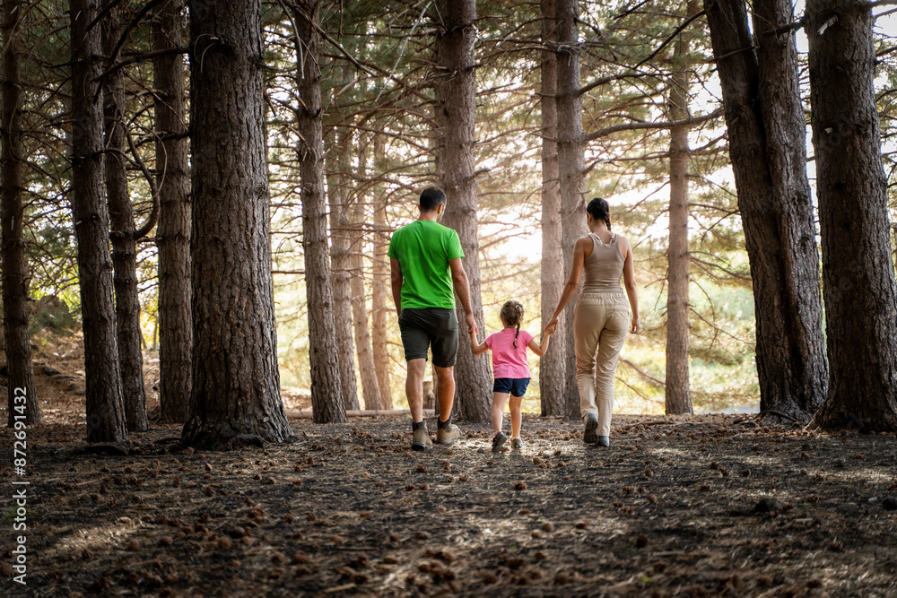 Fototapeta premium Family Walking in Forest - Outdoor Adventure and Quality Time - back view