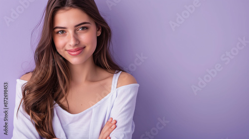 Portrait of a young latin woman with pleasant smile and crossed arms isolated on purple wall with copy space. 